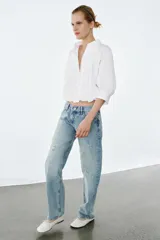 Jeans de tiro bajo y corte recto, con diseño de cinco bolsillos, trabillas en la cintura y efecto lavado con detalles de rotos en el frente.