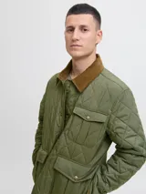 Campera acolchada de diseño matelaseado en color verde oliva, con cuello camisero en pana marrón, cierre frontal con botones a presión y bolsillos frontales con solapa.