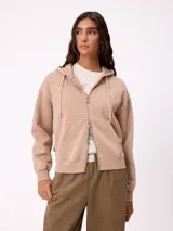 Canguro con cierre frontal de la marca Rusty, confeccionado en tejido de algodón y poliéster. Presenta capucha con cordones ajustables, bolsillos tipo canguro y puños acanalados.