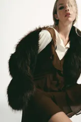 Abrigo corto de Zara confeccionado en pelo sintético de textura suave, color marrón oscuro. Presenta cuello solapa, manga larga y cierre frontal con ganchos metálicos ocultos.