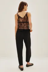 Pantalon de vestir negro de corte sastrero, con tiro medio, bolsillos laterales y botamanga con detalle de botón.