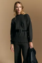 Polera de tejido de punto color negro, con cuello alto, mangas largas y diseño de líneas verticales en el ruedo. Presenta un corte relajado y una textura suave.
