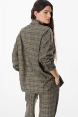 Camisa de corte oversize con estampado de cuadros, cuello clásico, cierre frontal con botones y bolsillo en el pecho.