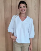 Remera blanca con cuello en V y mangas tres cuartos abullonadas con puños elásticos.