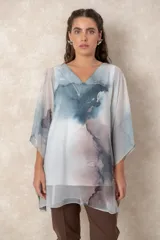 Blusa tipo túnica de gasa semitransparente con escote en V y mangas amplias. Presenta un diseño estampado con efecto acuarela en tonos azules, grises y marrones sobre fondo blanco.