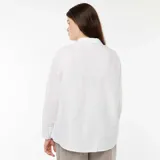 Camisa blanca de corte holgado, manga larga y cuello clásico.