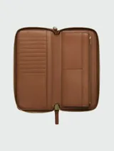 Billetera Marc Jacobs modelo The Continental, confeccionada en cuero color marrón. Presenta un diseño de apertura completa con cierre perimetral, múltiples ranuras para tarjetas, compartimentos para billetes y un bolsillo interno con cierre.