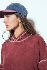 Buzo con capucha de calce relajado, confeccionado en tela con efecto lavado desgastado. Presenta costuras a la vista en color contrastante y un bolsillo frontal tipo canguro.