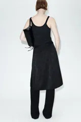 Falda midi de tiro medio en tejido jacquard con diseño floral tono sobre tono. Presenta un corte recto con una abertura lateral y cierre oculto con botón y cremallera.