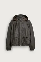 Cazadora de hombre relaxed fit confeccionada en tejido de lino y algodón con acabado encerado, color marrón oscuro. Cuenta con cuello subido, capucha ajustable con cordón, cierre frontal de cremallera metálica, mangas largas con puños elásticos, bolsillos frontales tipo parche con solapa en la cadera y acabado elástico en el ruedo.