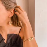 Par de caravanas doradas con forma de hoja colgante y brazalete dorado con forma de hoja.