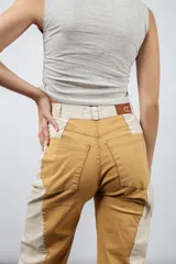 Pantalón de jean color mostaza con paneles laterales color crema, de corte recto y tiro medio.