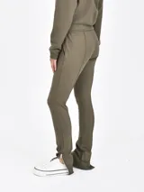 Pantalon deportivo color verde oliva, de corte ajustado con costuras frontales verticales y cierre en los tobillos. Cuenta con cintura elástica con cordón ajustable.