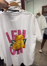 Remera blanca de manga corta y corte holgado con un estampado frontal que incluye una botella de vino, una copa de vino y la palabra "VINO" escrita al revés.