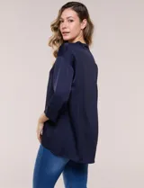 Camisa de satén azul marino con cuello mao, escote en V y mangas tres cuartos con hombro caído. Presenta silueta holgada, cierre frontal con botones y ruedo asimétrico.