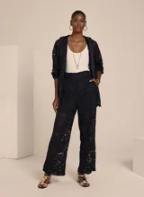 Pantalón de encaje negro con corte recto, tiro alto, cierre frontal con cremallera, dos bolsillos y forro incorporado.