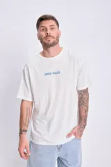 Remera de corte oversize color crudo, con cuello redondo, mangas cortas y estampa frontal con la frase 'Good Wave' en letras azules.