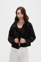 Campera corta de nylon en color negro, con cuello alto, capucha integrada y cierre frontal oculto con solapa.
