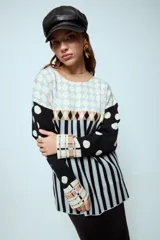 Sweater de punto con diseño geométrico y a rayas, de corte holgado y manga larga. Presenta un patrón combinado de lunares en las mangas, rombos en la parte superior y rayas verticales en el cuerpo.