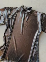 Polera de manga larga con acabado brillante color peltre, cuello alto y frunces sutiles en los hombros.