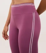 Legging deportiva de microfibra color violeta, con cintura alta y detalles de líneas blancas contrastantes en los laterales.