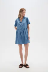 Vestido corto camisero de denim celeste, con cuello camisero, mangas cortas y falda acampanada con botones frontales.