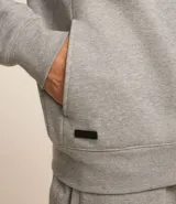 Buzo deportivo negro con capucha, cierre frontal con cremallera, bolsillos laterales y puños ajustados. Confeccionado en tejido de algodón y poliéster.