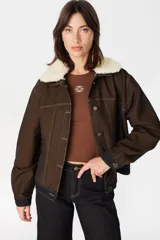 Chaqueta de denim color marrón con costuras en contraste, cuello de lana desmontable en color crema, cierre frontal con botones metálicos y bolsillos laterales.