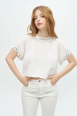 Blusa de manga corta color negro con escote redondo, decorada con pedrería brillante en el cuello y en los bordes de las mangas.
