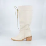 Bota de cuero color marrón con caña alta, taco de madera y cordones decorativos.