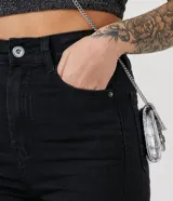 Pantalón skinny de tiro alto, confeccionado en denim negro con cierre de botón y cremallera. Cuenta con trabillas en la cintura y bolsillos funcionales tanto en la parte frontal como en la trasera.