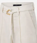 Bermuda de cintura mediana color beige, confeccionada en sarga, con trabillas, cierre tradicional, bolsillos y frisos delanteros. Incluye cinturón de tejido para lazo con hebilla metalizada.