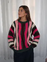 Buzo tejido de punto con diseño de rayas verticales anchas en tonos fucsia, verde oscuro, bordó, rosado y crudo, con cuello redondo, puños y ruedo acanalados.