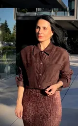 Camisa de gamuza color marrón, con cuello clásico, cierre frontal de botones y bolsillos delanteros tipo parche.