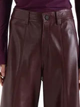 Pantalon de tiro alto y silueta wide leg, confeccionado en cuero. Presenta recortes frontales y laterales que estructuran la prenda y tajos en el ruedo que aportan movimiento.