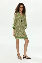 Vestido túnica corto de viscosa con estampado geométrico en tonos verdes y crudo, escote en V pronunciado tanto en el frente como en la espalda, mangas tres cuartos y diseño oversized.
