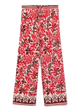 Pantalón largo de corte recto y tejido fluido, con estampado paisley en tonos rojo, bordó y crudo. Cuenta con cintura elástica con cordón ajustable y bolsillos laterales.