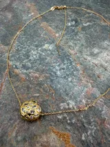 Collar de cadena fina dorada con dos dijes esféricos texturizados e incrustaciones de piedras de colores y zirconias.