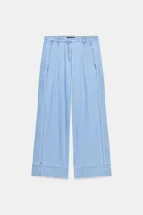 Jeans de tiro medio con corte wide leg y pinzas delanteras. Presenta bolsillos frontales, bolsillos de plastrón en la parte trasera, cierre frontal con cremallera, botón interior y ganchos metálicos.