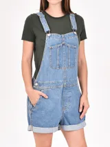 Monoprenda (jardinera) corta de denim color off-white, con tirantes ajustables y bolsillo frontal tipo pechera.