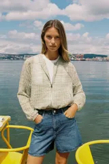 Cazadora de cuello redondo y manga larga, color verde claro con patrón a cuadros. Confeccionada en tejido de organza con estructura y acabados elásticos. Cierre frontal con cremallera y bolsillos delanteros.