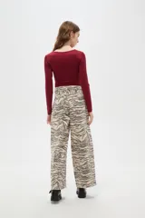 Pantalon de jean de corte ancho y tiro alto, con estampado animal print tipo cebra en tonos beige y gris.