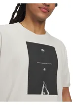 Remera de manga corta color beige con estampado gráfico central en negro que muestra a un jugador de básquetbol lanzando un tiro y la frase 'Greatest shooter of all time'.