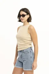 Musculosa de punto acanalado color beige, con cuello redondo, sisa ancha y un parche negro con logo en el pecho.