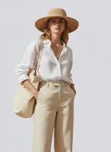 Sombrero de ala ancha tejido en rafia natural, con copa redonda.