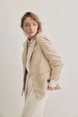 Blazer sastrero de lino color beige, de silueta relajada y líneas clásicas. Incorpora solapas tradicionales, cierre frontal de un botón y bolsillos de vivo.