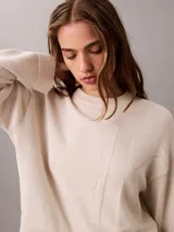 Sweater Calvin Klein de punto color blanco, de corte regular y manga larga, con cuello redondo y el logo de la marca en relieve en el pecho. Cuenta con puños y dobladillo acanalados.