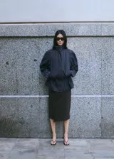 Parka oversize de tejido denim color azul oscuro, con cuello alto, mangas raglán largas, bolsillos laterales, cintura elástica y cierre frontal con botones ocultos.