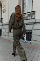 Chaqueta estilo bomber de color verde militar, confeccionada en tejido de efecto gamuza. Presenta cuello solapa, cierre frontal con cremallera metálica, bolsillos delanteros de vivo y bajo con acabado elástico.