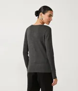 Suéter de punto color rosado, con cuello barco, mangas largas y puños con botones decorativos. El dobladillo también es acanalado.